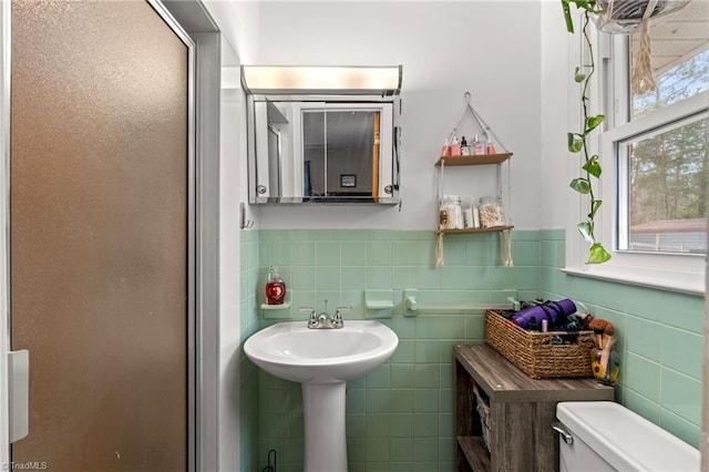 bathroom featuring a shower stall, toilet, tile walls, and wainscoting