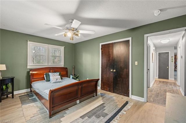 bedroom featuring light wood-style floors, baseboards, a closet, and ceiling fan