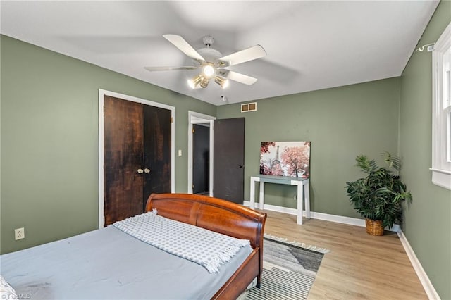 bedroom featuring a ceiling fan, visible vents, wood finished floors, and baseboards