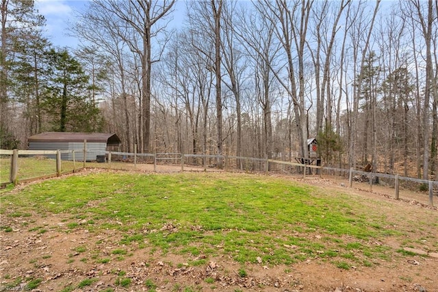 view of yard featuring a view of trees, an outbuilding, a pole building, and fence