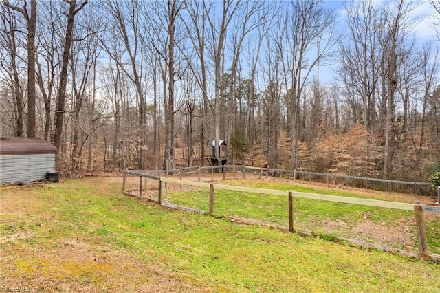 view of yard featuring an outbuilding, a storage unit, and fence