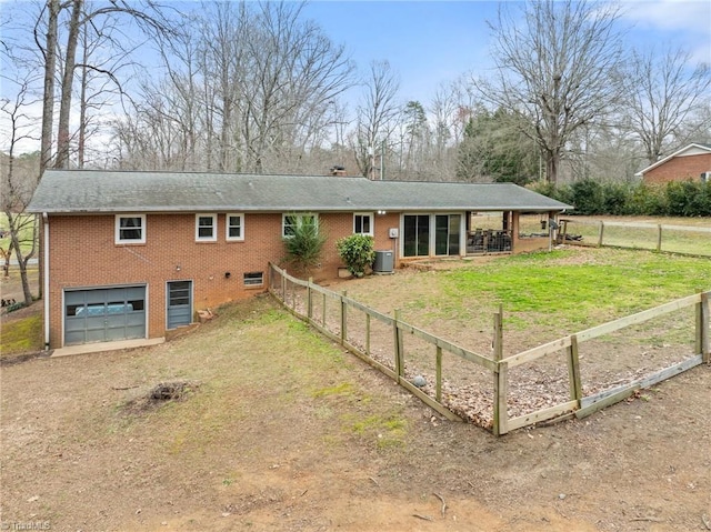 rear view of property featuring brick siding, fence, dirt driveway, cooling unit, and a garage