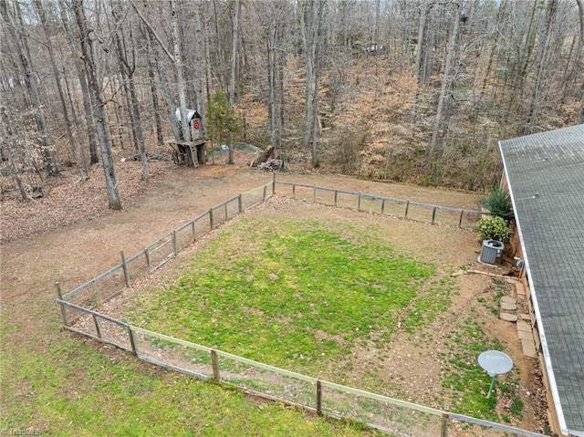 view of yard featuring a wooded view and fence