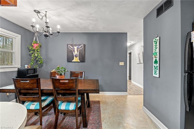 dining room with baseboards, visible vents, and a chandelier