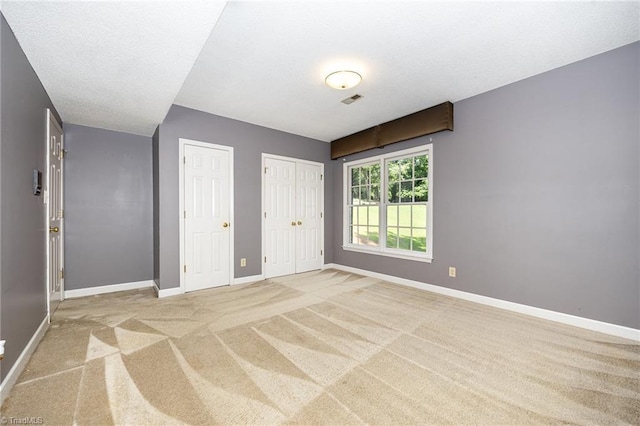 4904 Landaff Dr, Greensboro, NC 27406 - unfurnished bedroom featuring two closets, baseboards, and light carpet