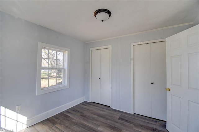 unfurnished bedroom featuring multiple closets and dark wood-type flooring