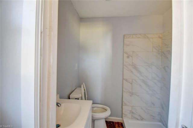 bathroom featuring tiled shower, vanity, and toilet