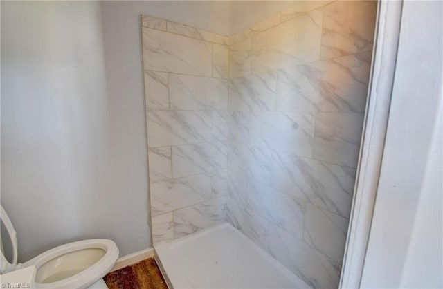 bathroom with toilet and tiled shower