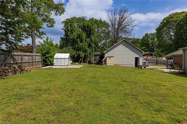 view of yard with a fenced backyard, a shed, and an outbuilding