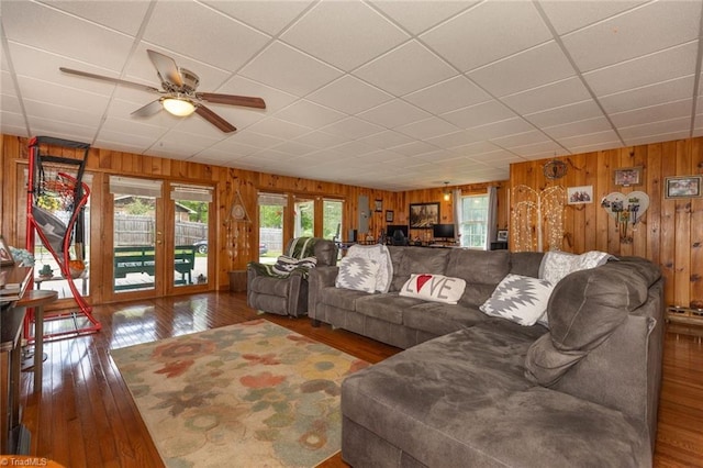 living room featuring wood walls, a paneled ceiling, a ceiling fan, and hardwood / wood-style floors