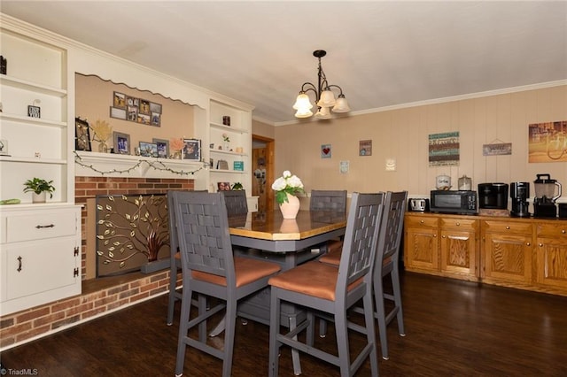 dining area featuring crown molding, built in features, dark wood-style floors, and an inviting chandelier