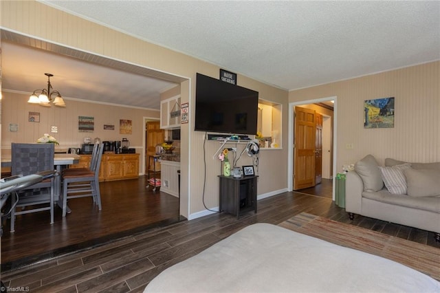 living room with dark wood-style floors, baseboards, an inviting chandelier, and ornamental molding