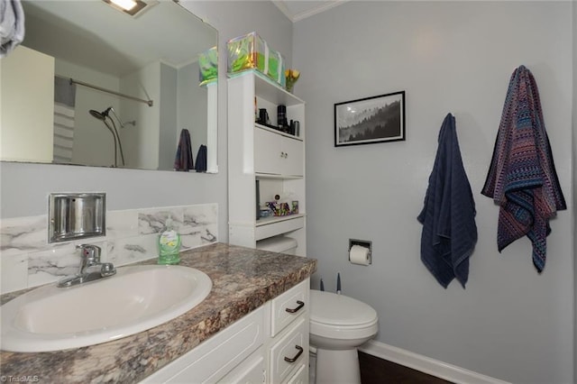 bathroom featuring vanity, ornamental molding, toilet, baseboards, and walk in shower