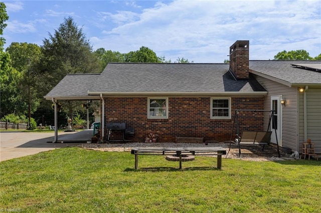 rear view of house with brick siding, roof with shingles, a yard, and a chimney