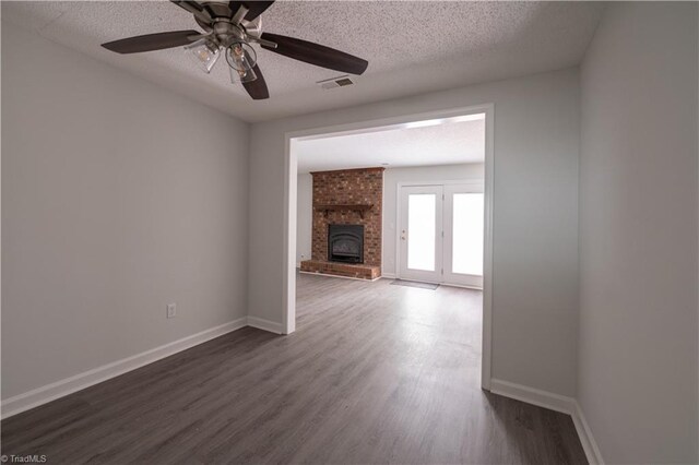909 Shelby Dr Unit B, Greensboro, NC 27409 - unfurnished living room with dark wood-type flooring, baseboards, ceiling fan, a textured ceiling, and a brick fireplace