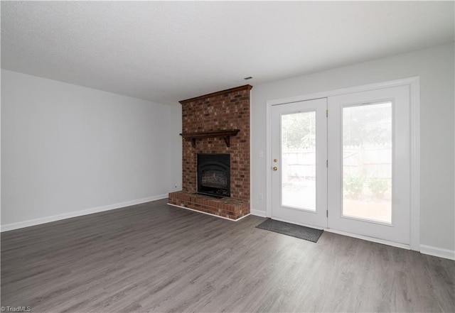 909 Shelby Dr Unit B, Greensboro, NC 27409 - unfurnished living room featuring wood finished floors, baseboards, and a brick fireplace