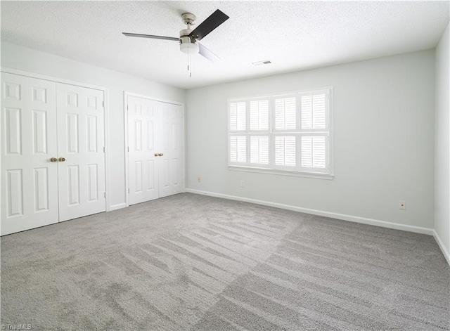 909 Shelby Dr Unit B, Greensboro, NC 27409 - unfurnished bedroom with two closets, carpet flooring, baseboards, a textured ceiling, and ceiling fan