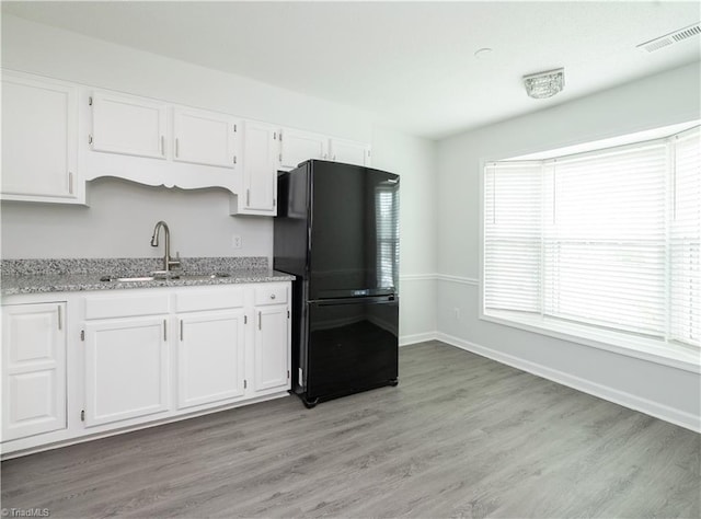 909 Shelby Dr Unit B, Greensboro, NC 27409 - kitchen with freestanding refrigerator, a sink, white cabinets, light wood finished floors, and light stone countertops