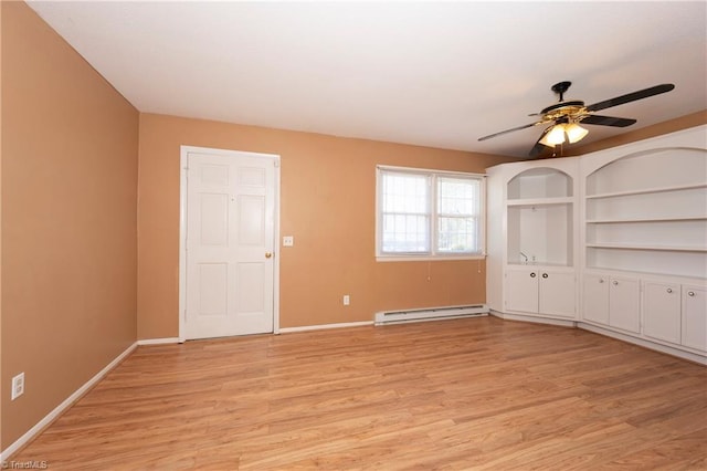 spare room featuring a baseboard heating unit, baseboards, and light wood finished floors