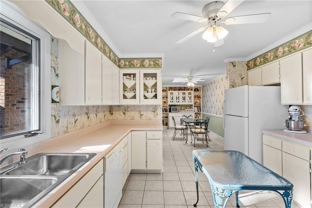 kitchen featuring white appliances, ornamental molding, white cabinets, light tile patterned flooring, and sink