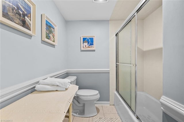 bathroom with shower / bath combination with glass door, toilet, and tile patterned floors