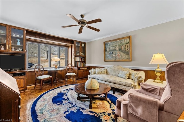 living room with ceiling fan, crown molding, wood walls, and parquet floors