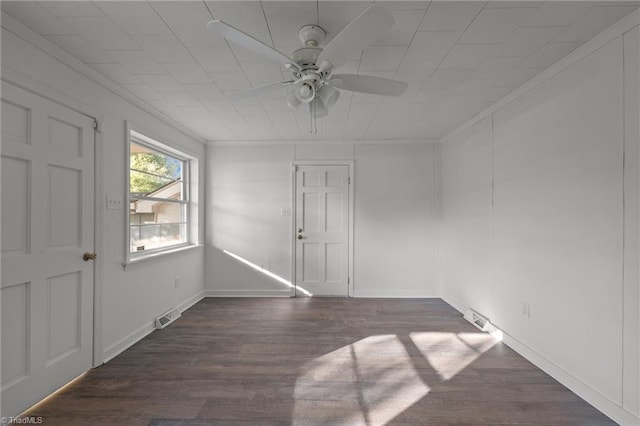 spare room featuring crown molding, dark wood-type flooring, and ceiling fan