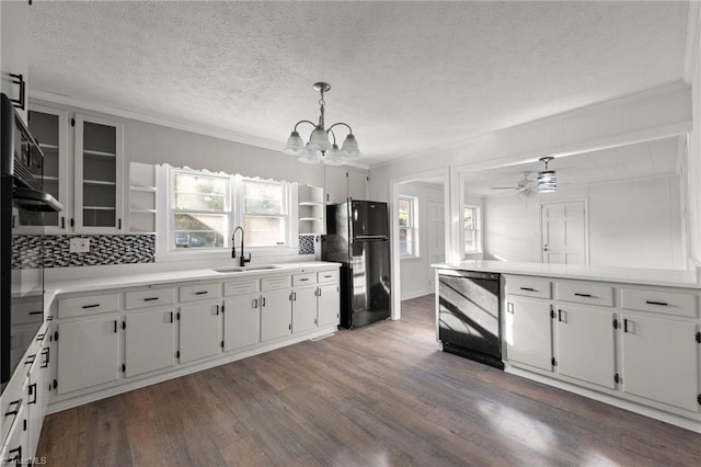 kitchen featuring sink, white cabinets, pendant lighting, and black fridge