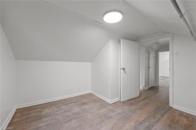 additional living space featuring vaulted ceiling and wood-type flooring