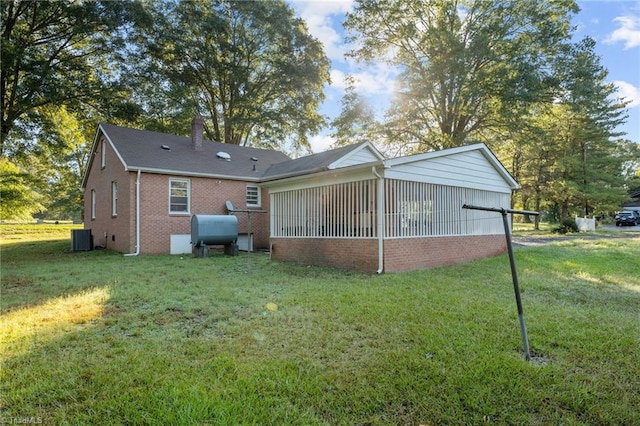 back of house with a yard, a sunroom, and central AC unit