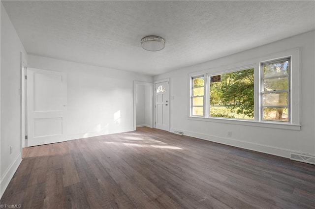 unfurnished room featuring a textured ceiling and dark hardwood / wood-style flooring