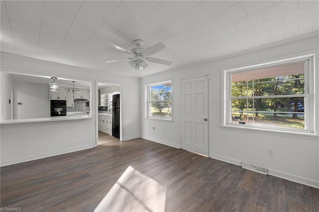 unfurnished living room with dark wood-type flooring, ceiling fan, a healthy amount of sunlight, and ornamental molding