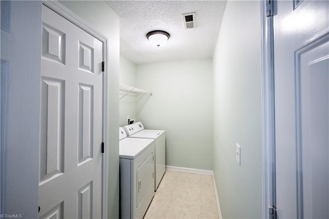 laundry area with washing machine and dryer and a textured ceiling