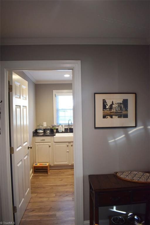 hallway with sink, crown molding, and light hardwood / wood-style flooring