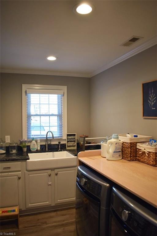 clothes washing area with washer and dryer, dark hardwood / wood-style floors, cabinets, crown molding, and sink