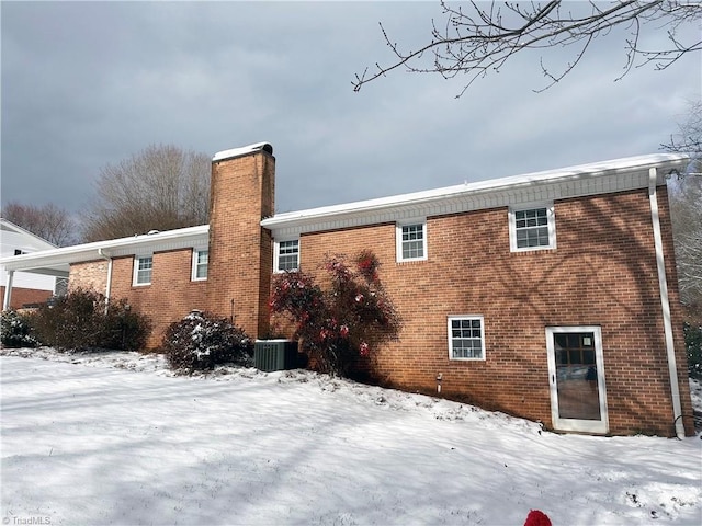 snow covered rear of property featuring cooling unit