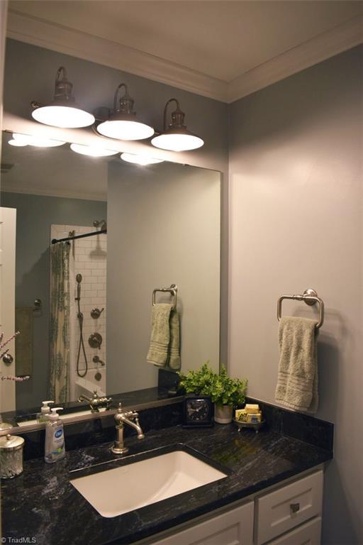 bathroom with walk in shower, vanity, and crown molding