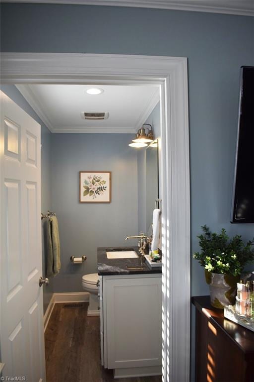 bathroom featuring toilet, vanity, wood-type flooring, and crown molding