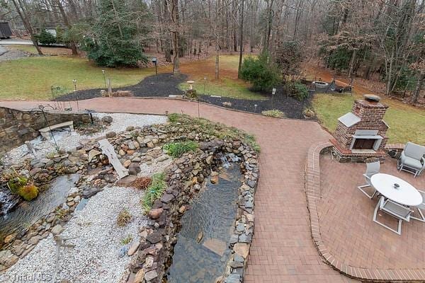 view of yard with exterior fireplace and a patio