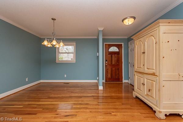 entrance foyer featuring ornamental molding, an inviting chandelier, and light wood-type flooring