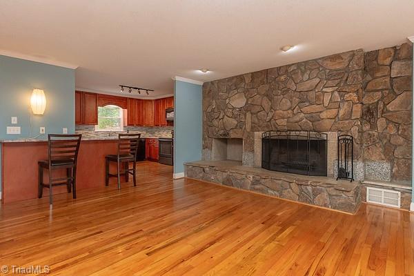 living room featuring ornamental molding, a fireplace, and light hardwood / wood-style flooring