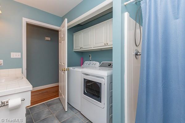 clothes washing area with cabinets, separate washer and dryer, sink, and dark tile patterned floors