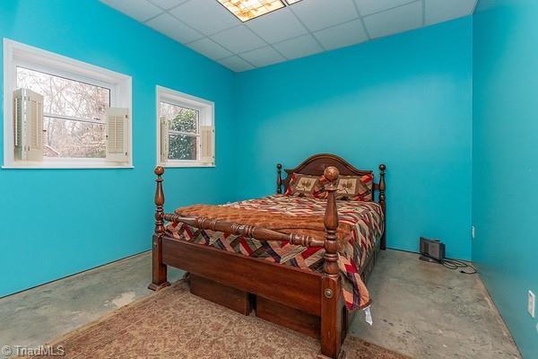 bedroom featuring a drop ceiling and concrete floors