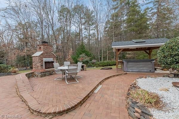 view of patio / terrace with an outdoor brick fireplace and a hot tub