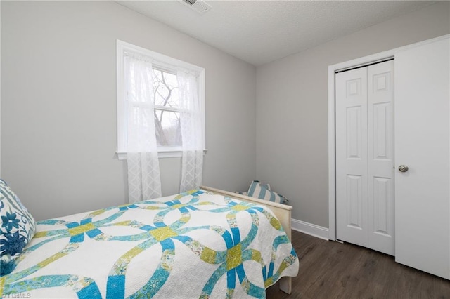 bedroom featuring dark hardwood / wood-style flooring, a textured ceiling, and a closet