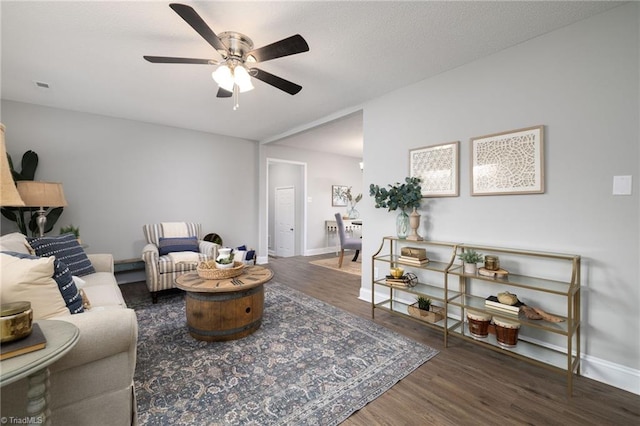 living room with ceiling fan and dark wood-type flooring