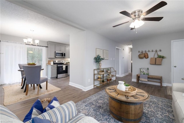 living room featuring a textured ceiling, dark hardwood / wood-style flooring, and ceiling fan with notable chandelier