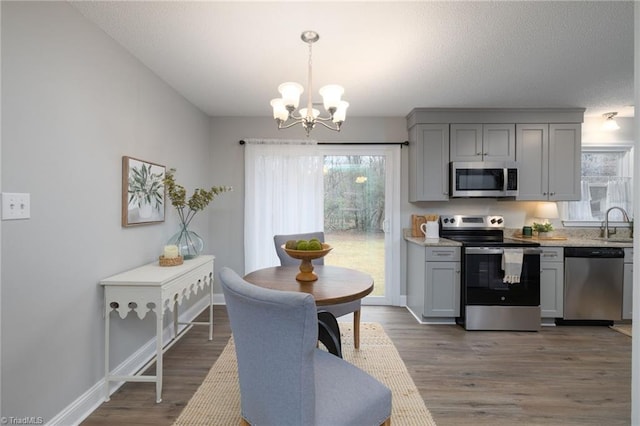 kitchen featuring gray cabinetry, hanging light fixtures, dark hardwood / wood-style flooring, a chandelier, and appliances with stainless steel finishes