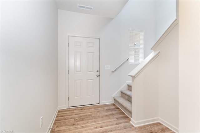 entryway with stairs, wood finished floors, visible vents, and baseboards