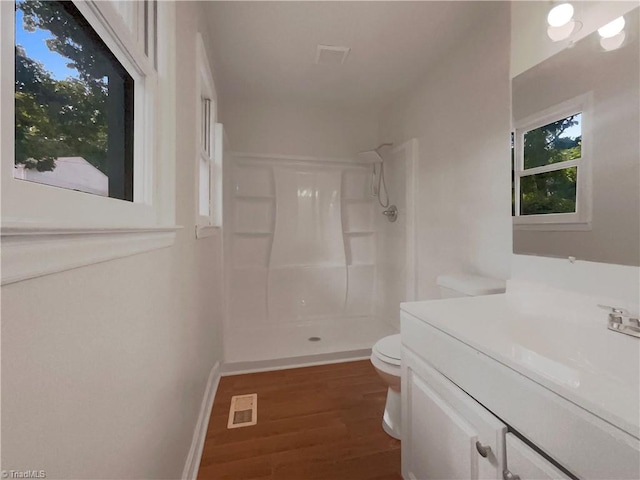 bathroom with hardwood / wood-style floors, vanity, toilet, and walk in shower